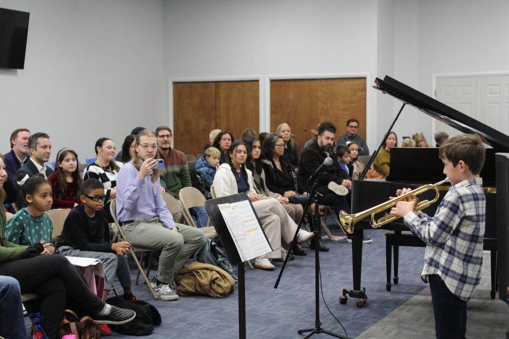 Families and children in a bright, welcoming music studio lobby at Chambers Music Studio in Columbus, Ohio, offering piano lessons and music classes for kids and adults in a community-centered environment.