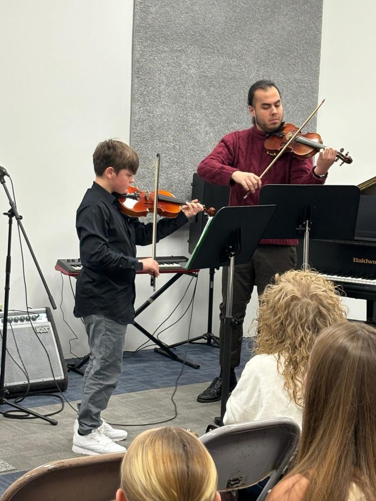 Violin teacher Louis Dhoore performs alongside February Student of the Month Myles Ambrosius during a Chambers Music Studio recital.