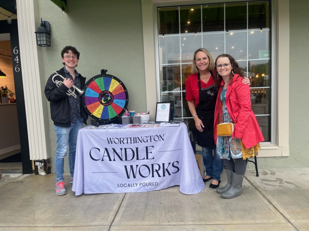 Chambers Music Studio team members standing outside Worthington Candle Works with a partner owner beside their co-branded market table setup.