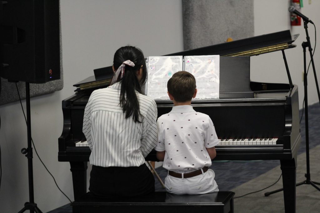 Child practicing piano and building focus through music lessons.