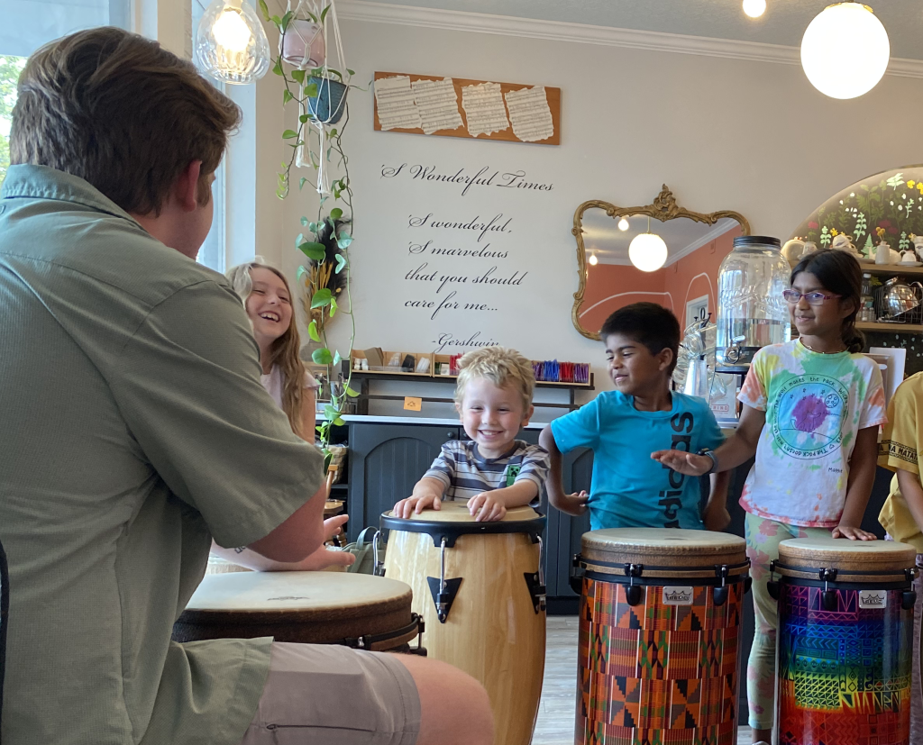 Students learning through hands-on instruments and musical activities during a summer program.